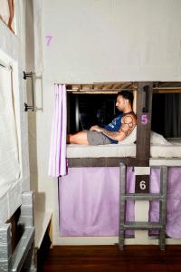 un hombre sentado encima de una litera en Sansa Beach Hostel, en Dubái