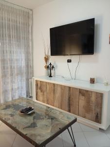 een woonkamer met een tafel en een tv aan de muur bij Cari Dei Home in Napels