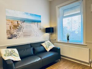 ein Wohnzimmer mit einem Sofa und einem Gemälde eines Strandes in der Unterkunft Rockcliffe Retreat, Stylish Coastal Apartment in Whitley Bay