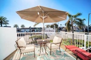 un patio con mesa, sillas y sombrilla en Little Inn By The Bay Newport Beach Hotel en Newport Beach