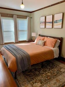 um quarto com uma cama grande com lençóis e almofadas laranja em Historic Downtown Riverview Flat, No. 2 em Astoria