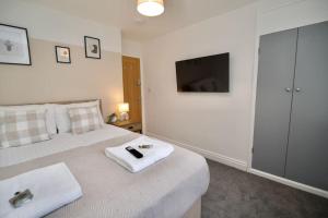 1 dormitorio con 1 cama y TV en la pared en Hall Lane House - Stunning 4Bed 5 mins Walk to Coventry Hospital, Must See!, en Coventry