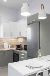 una cocina con nevera de acero inoxidable y armarios blancos en Harmony Luxury Apartment, en Ierápetra