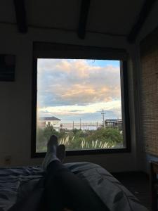 una persona tumbada en una cama mirando por una ventana en Oikos, en Punta del Diablo
