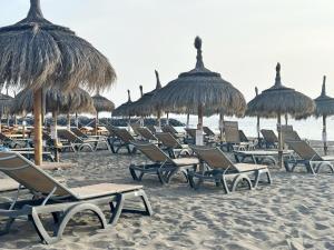 a bunch of chairs and straw umbrellas on a beach at Relaxing Ocean View, Spacious Art Apartment With Large Terrace, Near Best Costa Adeje Beaches in Adeje