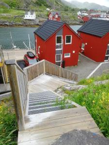 a red building with a ramp next to a parking lot at Waterfront Suite l Ballstad l Lofoten l Norway in Ballstad