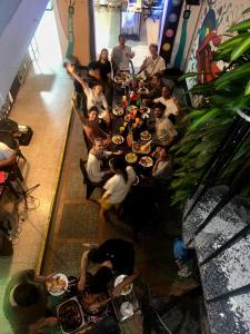 Rock Hostel Medellin في ميديلين: مجموعة من الناس يجلسون على طاولة طويلة يأكلون الطعام