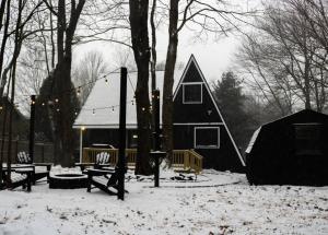 una casa negra en la nieve con un patio en The New Luxury Cabin PetFriendly Pocono Summit en Pocono Summit