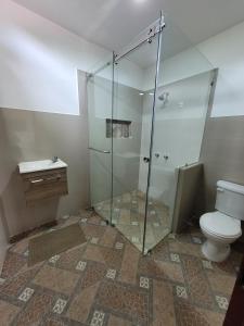 ein Bad mit einer Glasdusche und einem WC in der Unterkunft Palmendros Hosteria in Montañita