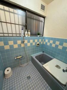 baño de azulejos azules con bañera y lavamanos en Nana House Ekoda - Private House, en Tokio