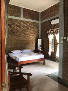 a bedroom with a bed and a brick wall at Griya Nareswara in Piyungan