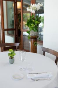 un tavolo bianco con due bicchieri e un vaso con fiori di Villa Battibecco a Loreto