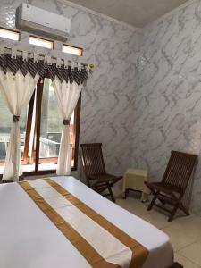 a bedroom with a bed with curtains and two chairs at Griya Nareswara in Piyungan