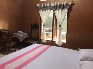 a bedroom with a bed with a window and a table at Griya Nareswara in Piyungan