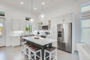 a kitchen with white cabinets and a stainless steel refrigerator at Beach Village Resort By Liquid Life in Gulf Shores