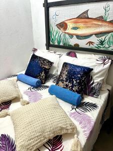 uma cama com almofadas e uma foto de um peixe em Suíte Capixaba - 06 em Gravatá
