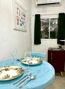 uma mesa azul com dois pratos e taças de vinho em Suíte Capixaba - 06 em Gravatá