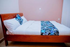 uma cama com lençóis brancos e almofadas azuis em Gmasters Homes kibagabaga em Kigali