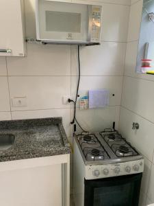 uma pequena cozinha com fogão e micro-ondas em Porto Paraty Residencial em Paraty