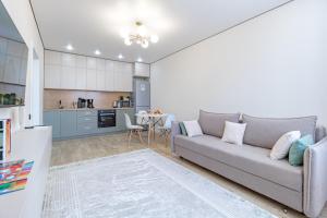 ein Wohnzimmer mit einem Sofa und einer Küche in der Unterkunft Apart Astana, ЖК Сыганак, д 32 рядом с Хан-Шатыром in Astana