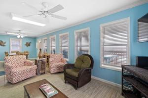 uma sala de estar com uma cadeira, um sofá e janelas em Gulf Front Beach House Sleeps 12 em Gulf Shores