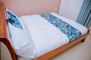 a bed with a blue and white blanket on it at Gmasters Homes kibagabaga in Kigali