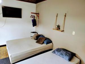 1 Schlafzimmer mit 2 Betten und einem Flachbild-TV in der Unterkunft Suíte privativa acesso rápido 5 minuto balsa in Ilhabela