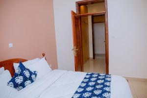 a bedroom with a bed with blue and white pillows at Gmasters Homes kibagabaga in Kigali