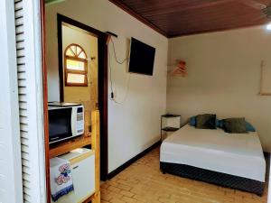 ein kleines Schlafzimmer mit einem Bett und einer Mikrowelle in der Unterkunft Suíte privativa acesso rápido 5 minuto balsa in Ilhabela