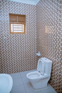 a bathroom with a toilet and a window at Gmasters Homes kibagabaga in Kigali