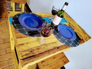 einen Holztisch mit zwei blauen Platten und Weingläsern in der Unterkunft Suíte privativa acesso rápido 5 minuto balsa in Ilhabela