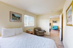 Un dormitorio con una cama blanca y una silla. en Seal Three Condo Getaway, en Lincoln City