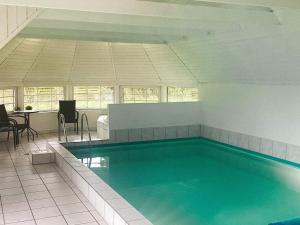 a swimming pool in a room with a table and chairs at Holiday home Væggerløse XXXVIII in Marielyst