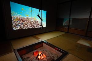 a room with a fire pit and a large tv at Minsyuku Mirai - Vacation STAY 94810v in Tokamachi