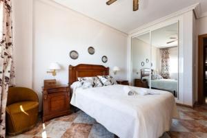 een slaapkamer met een bed, een stoel en een spiegel bij Fuengirola Primera Línea de Playa in Fuengirola