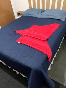 uma toalha vermelha está sentada numa cama azul em kitnet para casal em Taguatinga-DF em Brasília
