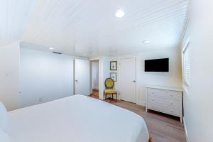 Un dormitorio blanco con una cama y un televisor. en Seaside Serenity, en Port Aransas