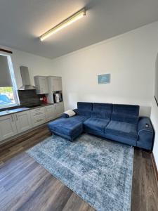a living room with a blue couch and a kitchen at Ben Lomond Apartment in Alexandria