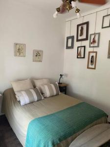 a bed in a bedroom with pictures on the wall at La Casita de Bogado in Boulogne