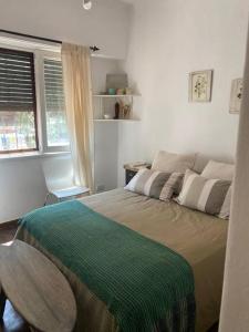 La Casita de Bogado في Boulogne: غرفة نوم مع سرير مع بطانية خضراء عليه