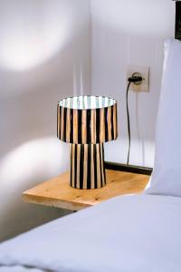 a small striped lamp sitting on a night stand next to a bed at Giraffe Hostel -Sea View Rooftop in Essaouira