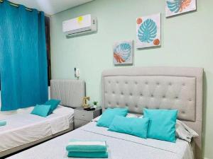 two beds with blue pillows in a bedroom at Apartamento Samaria Club Resort in Santa Marta