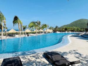 einen Pool mit Stühlen und Sonnenschirmen am Strand in der Unterkunft Apartamento Samaria Club Resort in Santa Marta