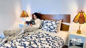 uma mulher deitada na cama a ler um livro em Charming Country House em Altares