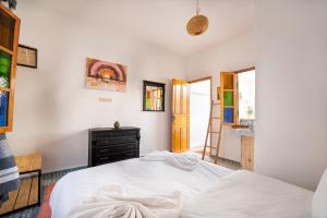 a bedroom with a white bed and a bathroom at Giraffe Hostel -Sea View Rooftop in Essaouira