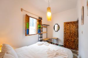 una camera con un letto bianco e una finestra di Giraffe Hostel -Sea View Rooftop a Essaouira
