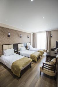 Habitación de hotel con 3 camas y TV en Tbilisi Inn, en Tiflis