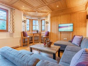 uma sala de estar com sofás azuis e uma televisão em Spykerhütte em Rauris