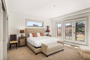 a bedroom with a bed and a chair and windows at Homestead Townhome in Snowmass Village