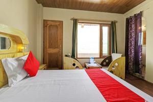 a bedroom with a red and white bed with a window at OYO Flagship Aman Cottage in Manāli